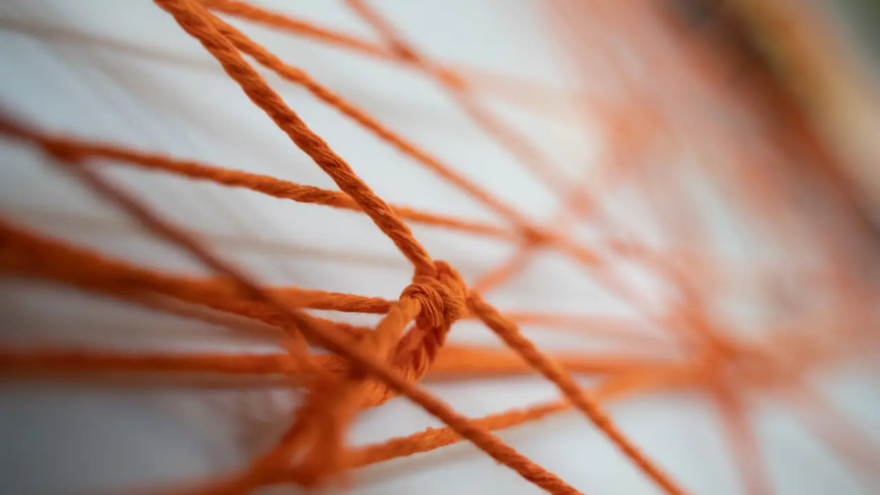 Closeup view of bright orange thread, knotted and going in different directions