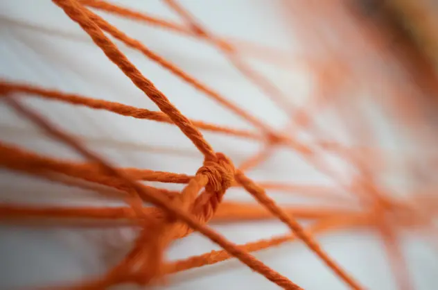 Closeup view of bright orange thread, knotted and going in different directions