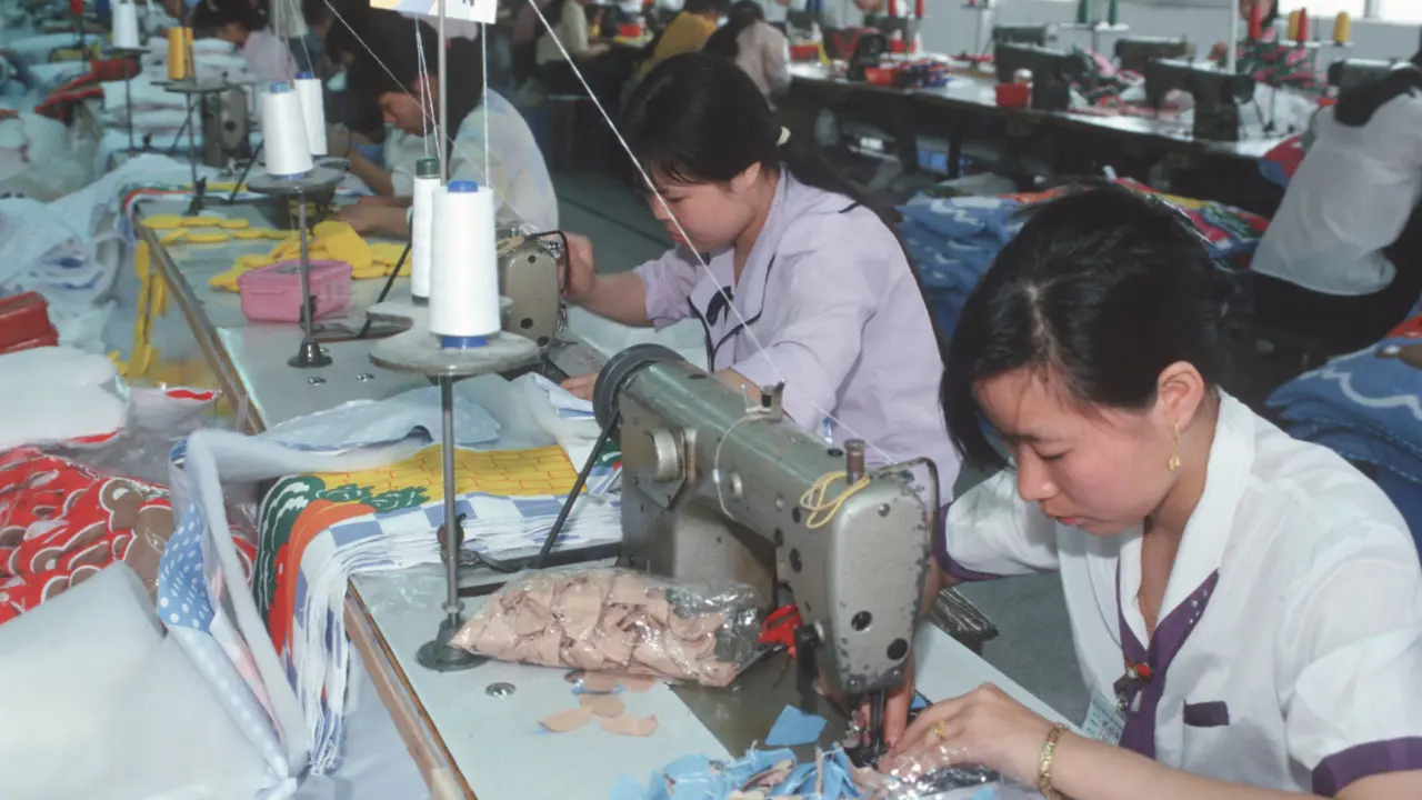 Two women at workstations operating industrial sewing machines