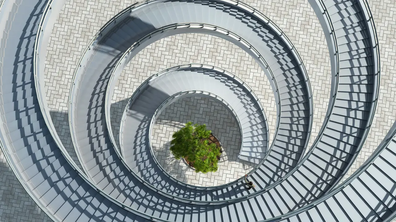 An aerial view of an outdoor spiral staircase with a single tree at the bottom in the centre