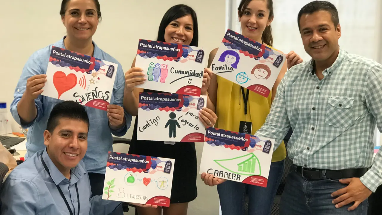 A group of people smiling and holding up hand drawn posters