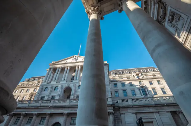 The facade of an intricate building with pillars, arches and many decorative windows. The view is from a low perspective, with the building towering above and some pillars in the foreground.