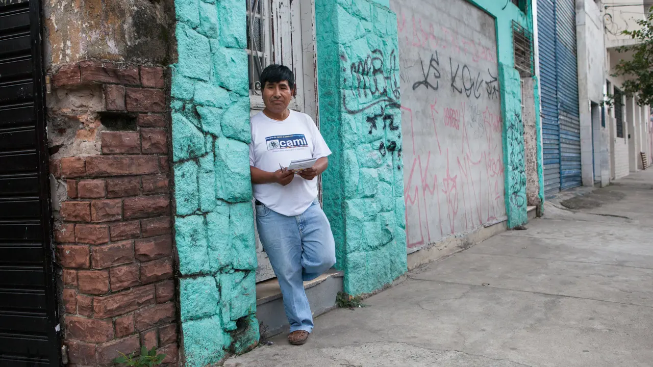 A man in casual clothing leaning against a wall with graffiti