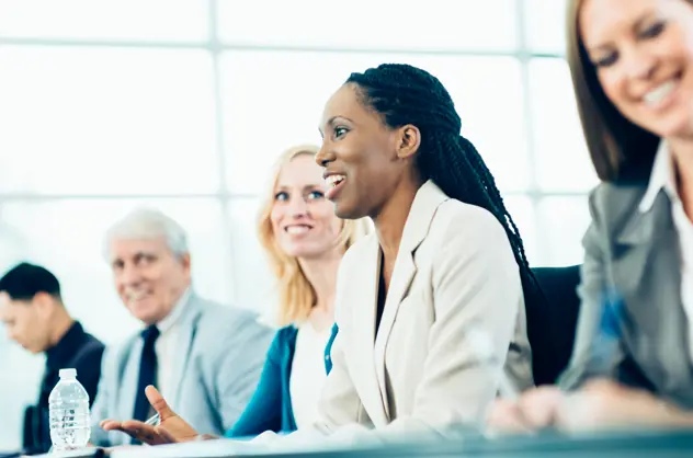A group of smartly dressed people sitting at a desk in a corporate workshop
