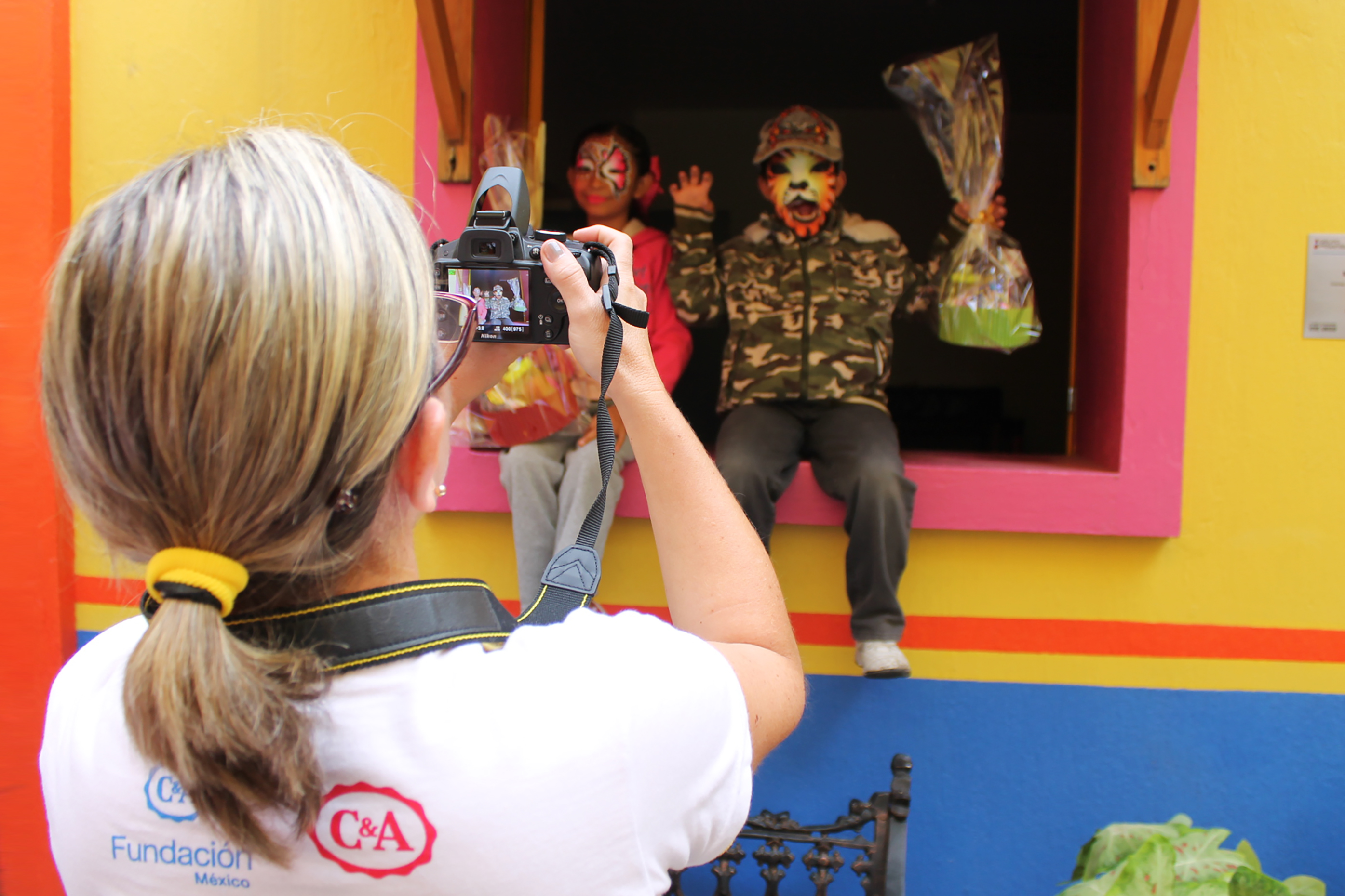 woman taking a photo of two children wearing facepaint