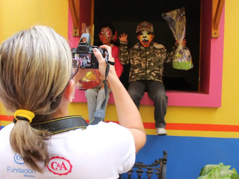 woman taking a photo of two children wearing facepaint