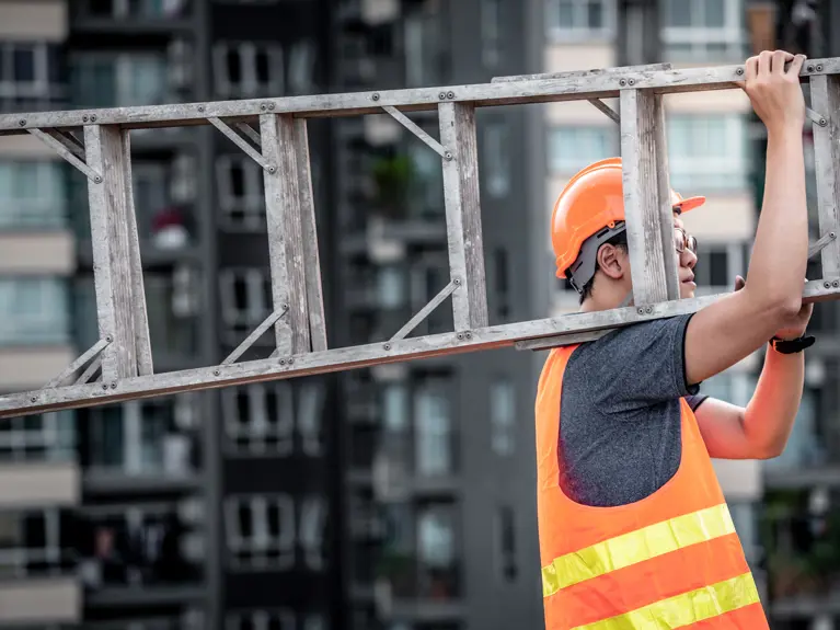 builder holding a wooden ladder