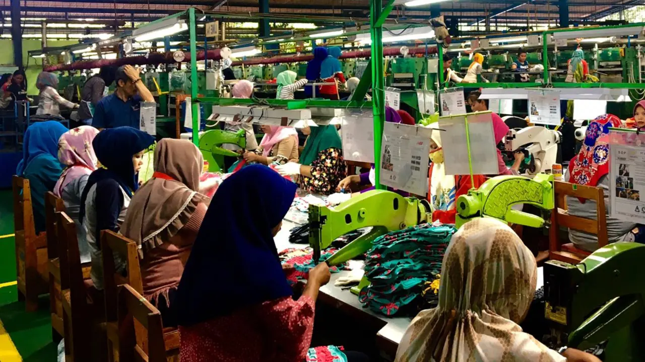A busy textile factory with many workers operating sewing machines